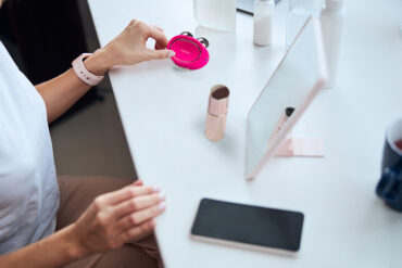 Photo of a FOREO BEAR 2 microcurrent device on a table, with SUPERCHARGED Serun, mobile phone, a cup of tea, a mirror, and hands