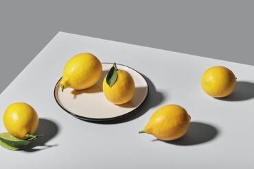Still life photography of five lemons on the table and a plate.