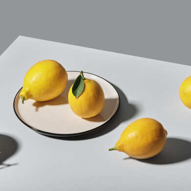 Still life photography of five lemons on the table and a plate.
